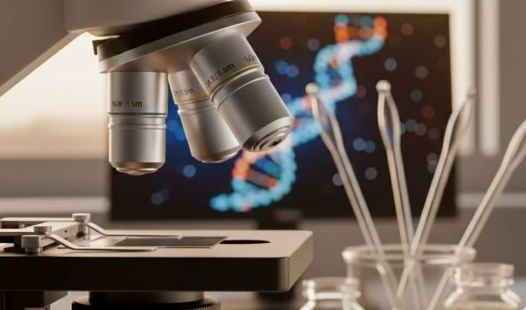 Mikroskop im Forschungslabor mit DNA-Darstellung auf Bildschirm und Glasgefäßen